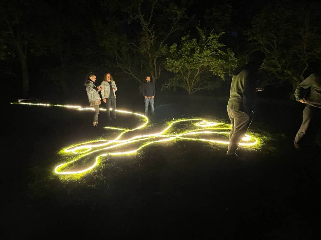 A rope of light laid in curves across dark grass at night