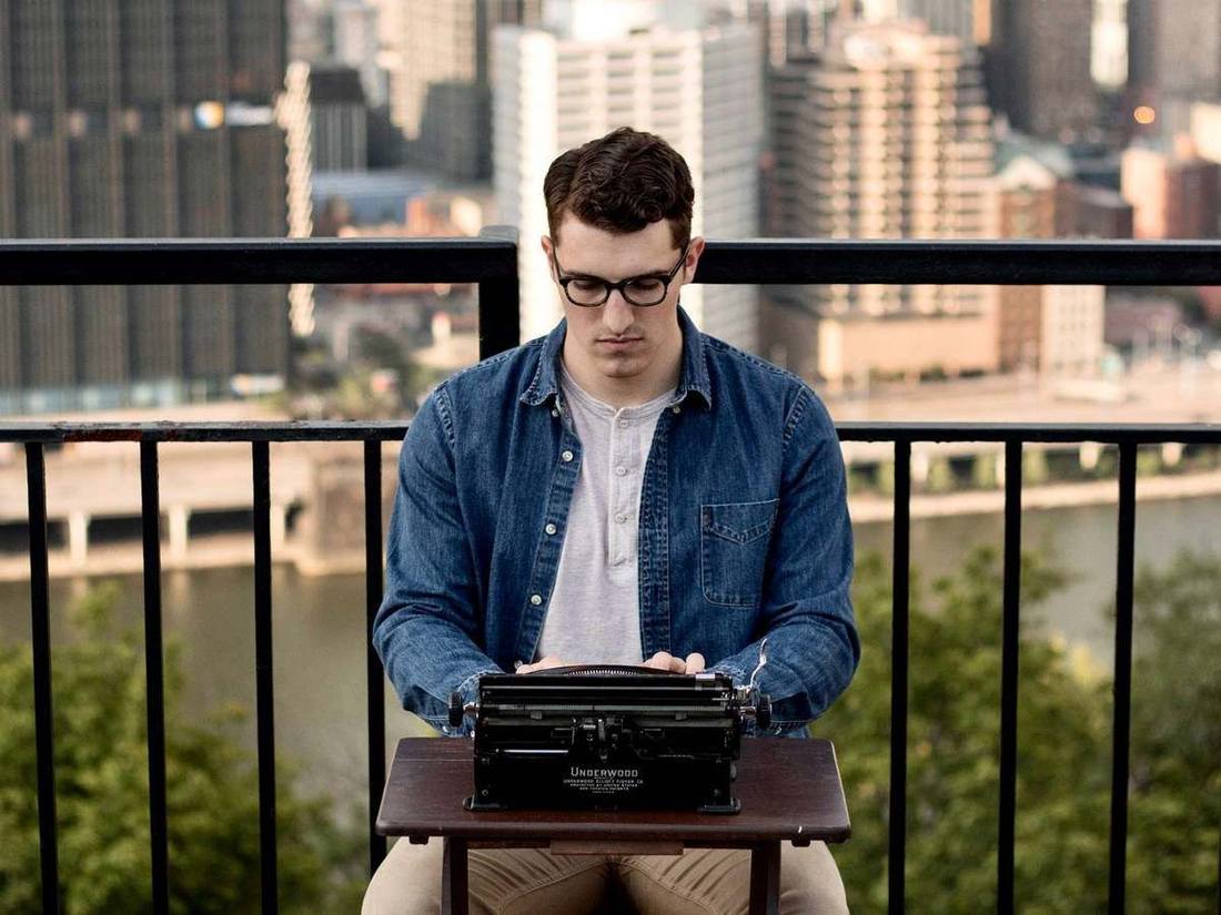 At a typewriter on a balcony above the Pittsburgh rivers