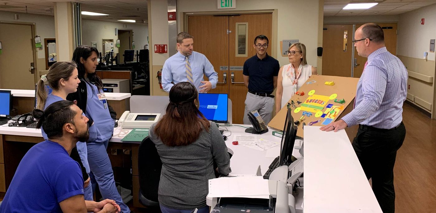Clinicians gathered at a nurses' station around a cardboard prototype