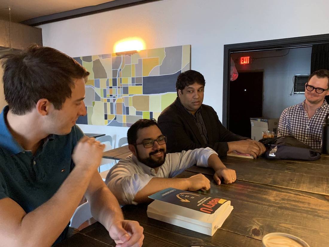 Four of us around a long wooden table with a copy of Theory U on it