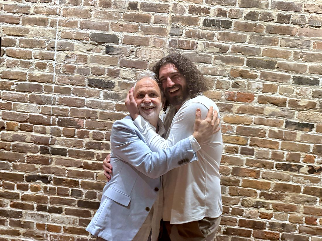 Samir and I mid-hug against a brick wall, both laughing