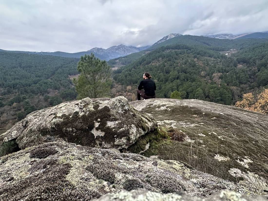 Sitting cross-legged on the mossy rock looking out over the valley