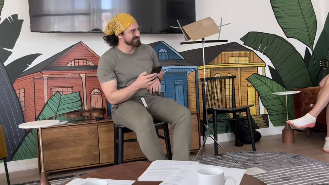 Sitting up front in a yellow bandana and joggers, facilitating