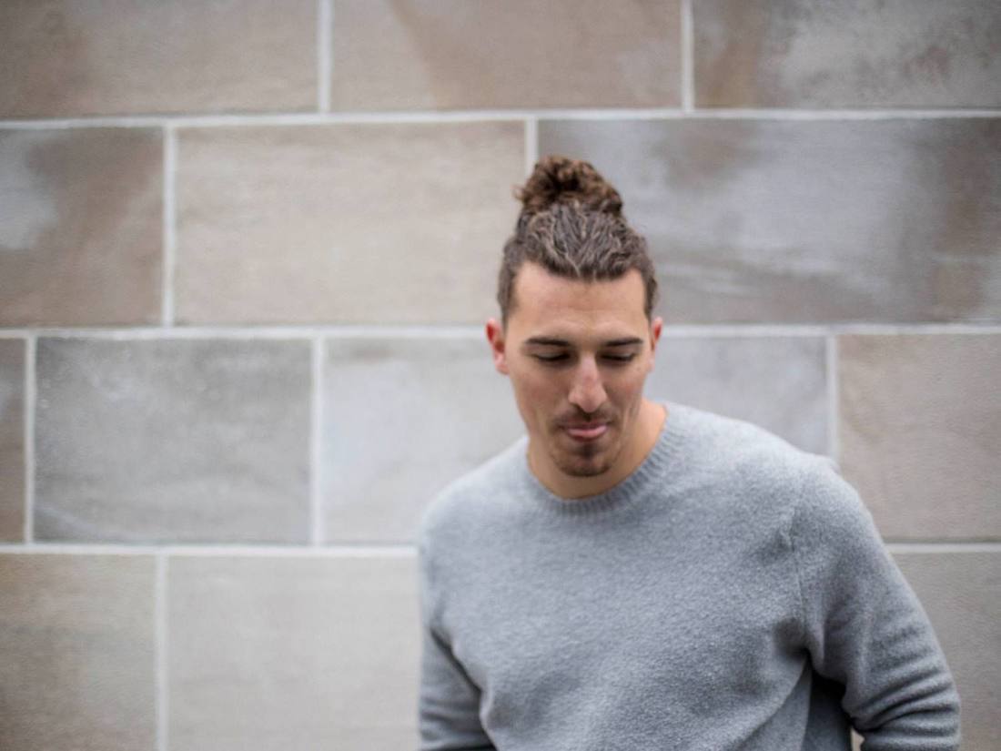 Standing against a stone wall, head lowered