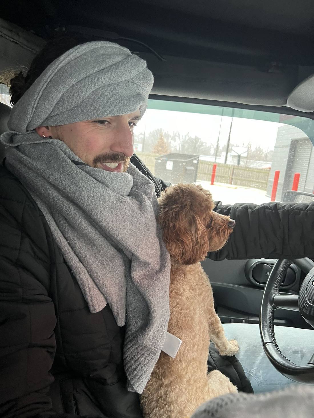 Wrapped in a fleece scarf at the wheel of the Jeep with Coco on my lap